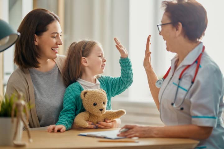 girl making high five with pediatric nurse