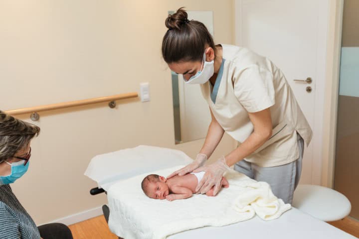 pediatric nurse doing physical examination on newborn