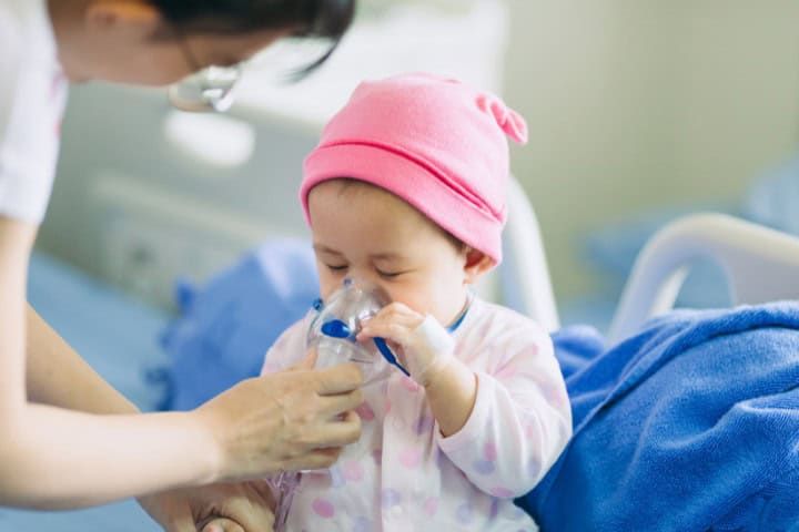 Healthcare professional assisting a young child with a respiratory mask in a clinical environment