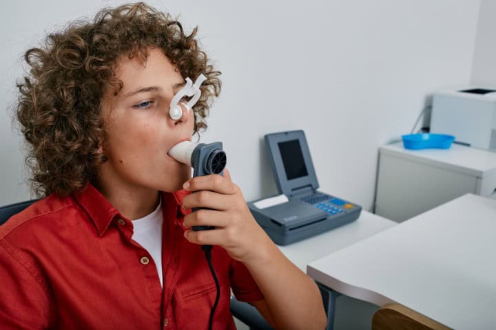 Young patient undergoing pulmonary testing with a spirometer and nasal clip in a clinic setting