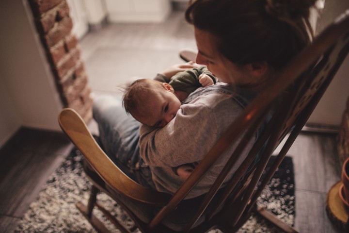 Mother gently rocking her baby in a cozy, dimly lit room