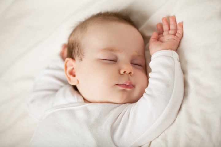 A newborn baby sleeps soundly on a soft surface