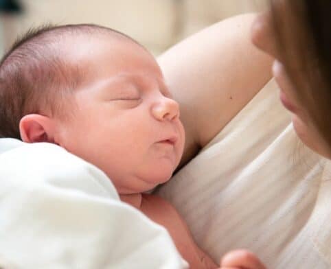 Newborn baby peacefully sleeping in the arms of the mother