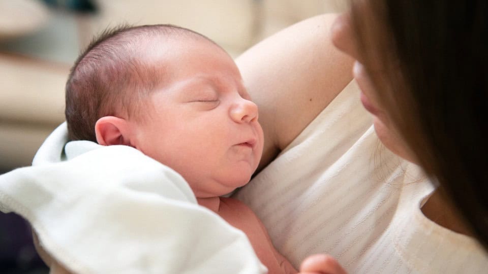 Newborn baby peacefully sleeping in the arms of the mother