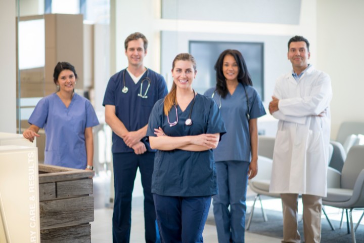 Team of pediatricians and nurses standing in a clinic lobby, wearing scrubs and lab coats