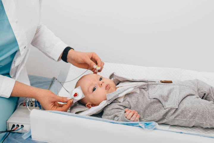 Pediatrician conducting an audiology test on a newborn