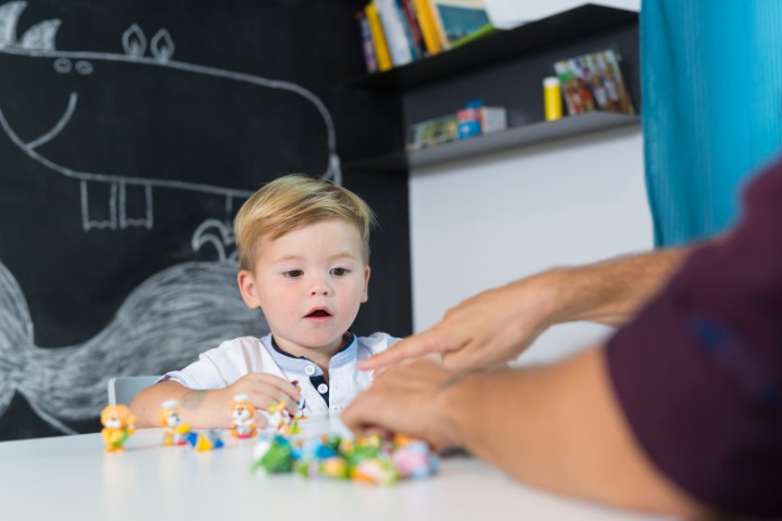 Therapist using toys to support a young boy's speech development in a session