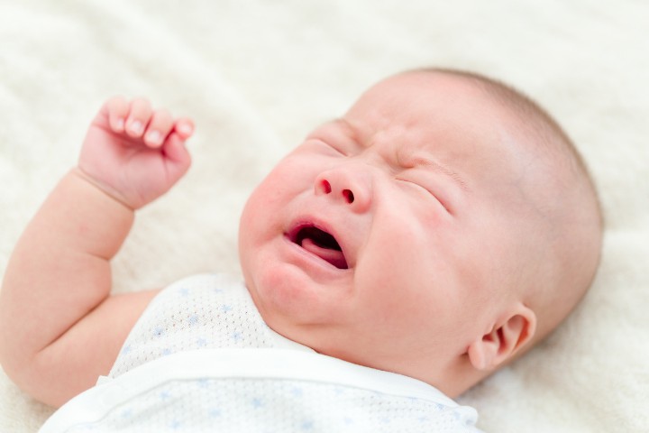 A crying newborn with feeding problems, possibly due to latch or tongue-tie issues.