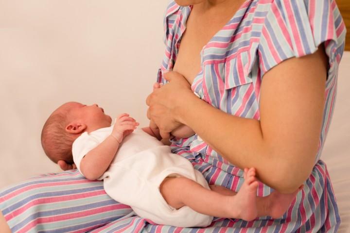 A mother experiencing breastfeeding difficulties while nursing her newborn baby