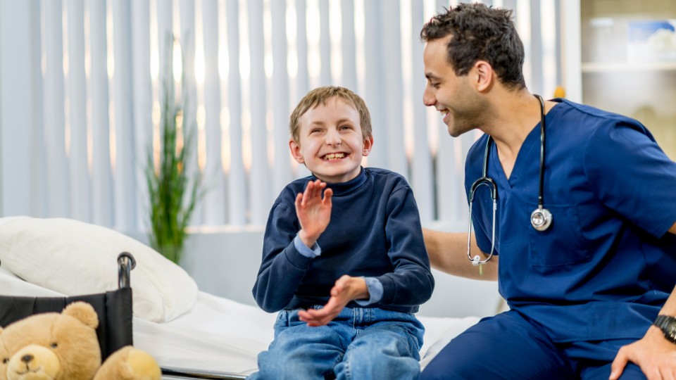 A developmental pediatrician alongside a smiling child with a disability