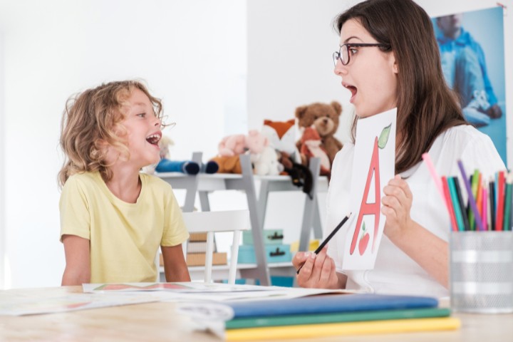 Speech therapist using visual aids to help a child with early intervention for developmental challenges