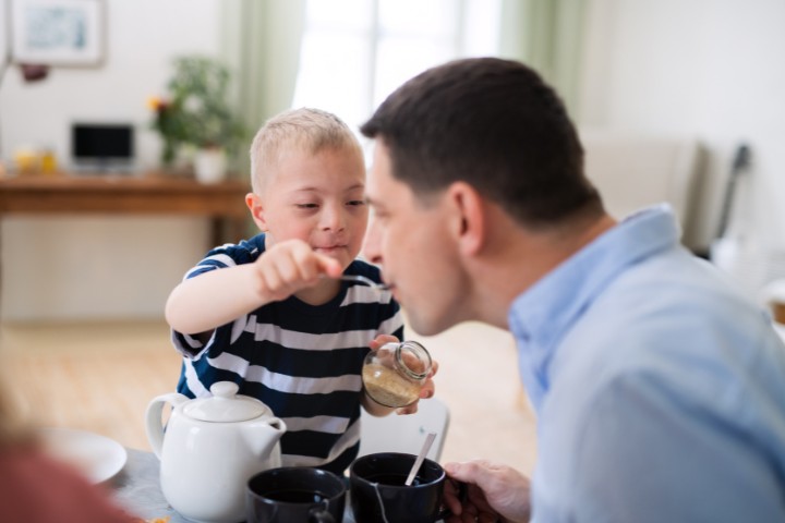 Child with Down syndrome engaged in a feeding activity with his father