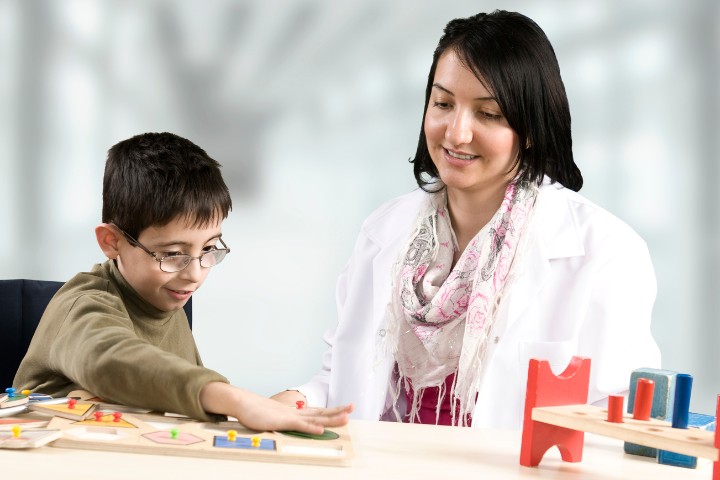 A developmental pediatrician guides a child with developmental challenges through a hands-on learning activity