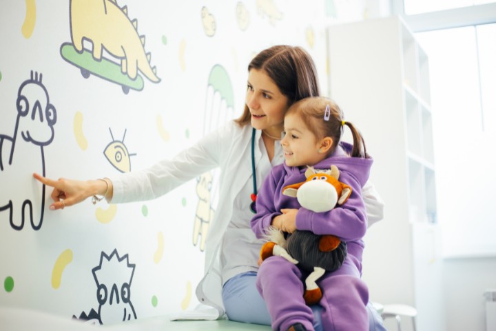 Child sitting with a pediatrician in a colorful clinic environment, focusing on interactive developmental activities