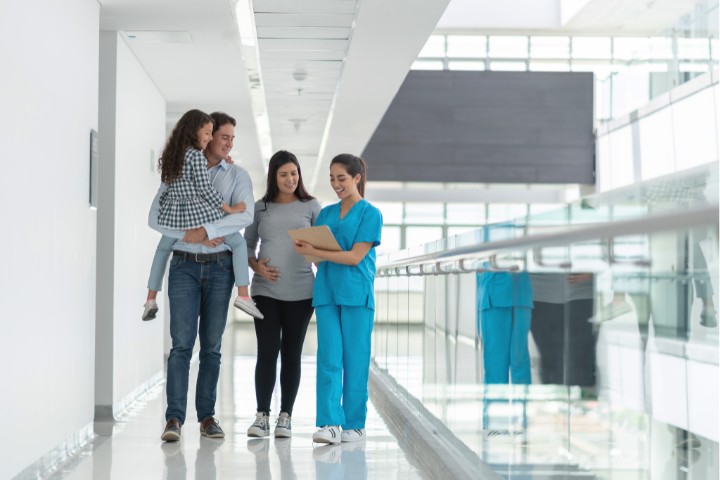 A family walking with a nurse in a bright pediatric clinic hallway during a consultation appointment