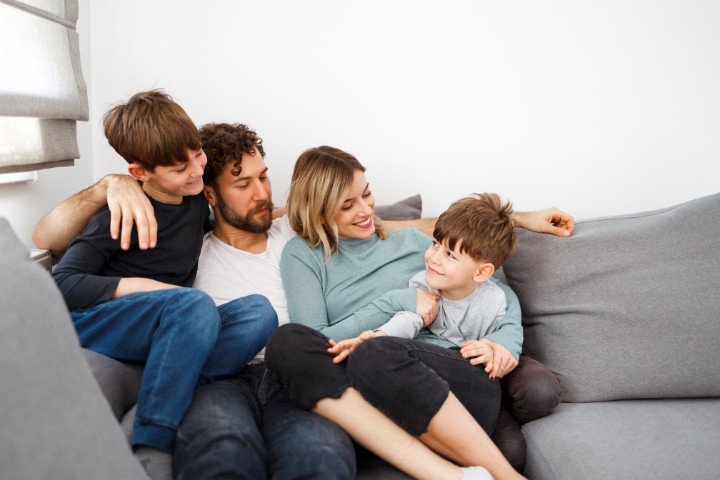 A family sitting together on a couch, discussing a virtual pediatric care appointment