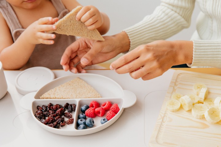 Child and parent engaging in a feeding activity with a focus on healthy food choices and hand coordination