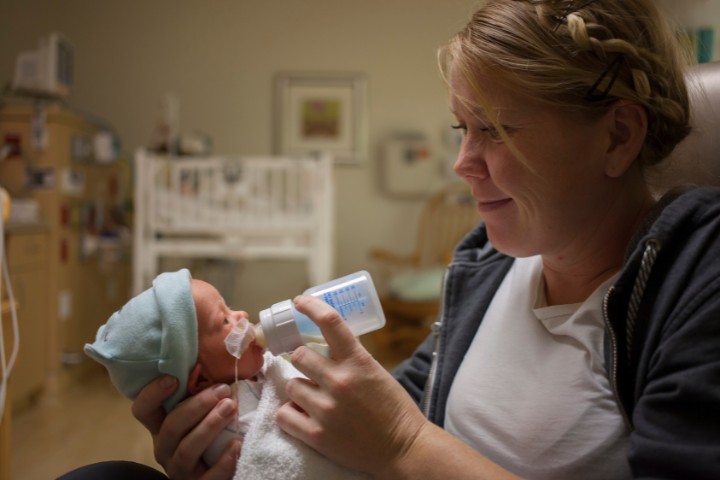 Premature baby receiving feeding support from a mother using a bottle