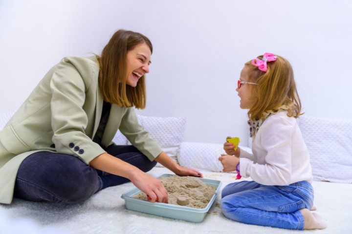 Interactive pediatric feeding therapy session with a girl using sand as sensory tool