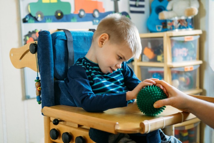 boy with cerebral palsy engaging in sensory therapy using a textured ball to improve motor skills