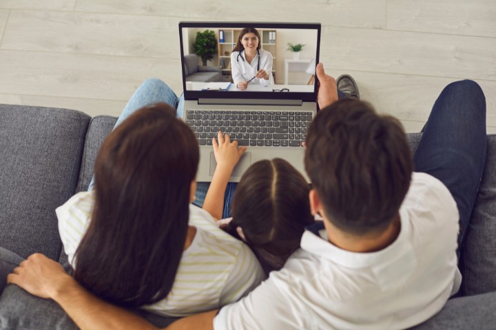 Parents and child sitting together on a couch during an online pediatric care session