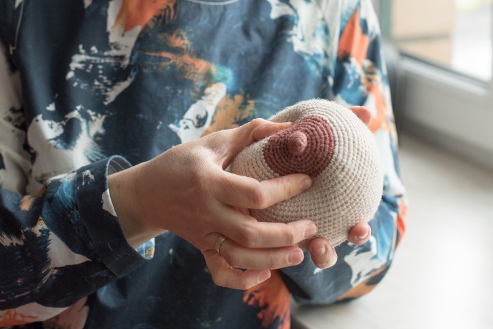 Lactation consultant demonstrating breast anatomy with a knit breast model to educate mothers on breastfeeding techniques