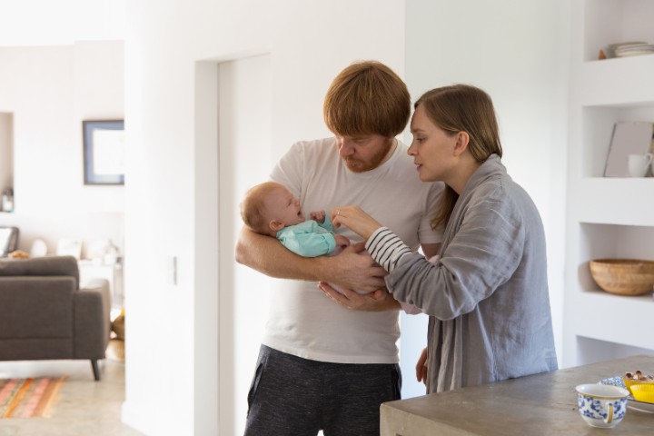 Parents comforting their baby at home to ease agitation while observing auditory responses