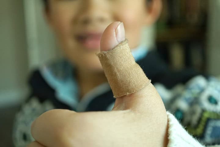 Close-up of bandaged child’s thumb for post-wart removal treatment care