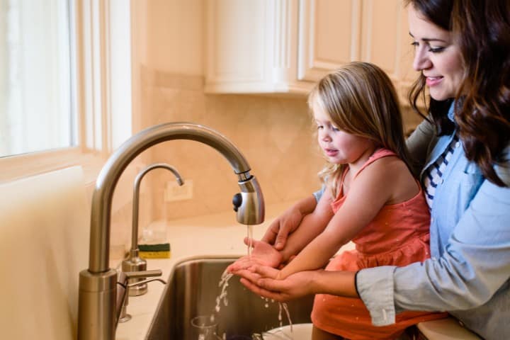Parent helping child wash hands for cryotherapy wound hygiene