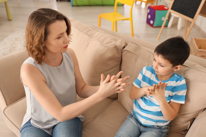 Professional therapist and child practicing hand gestures during autism support session