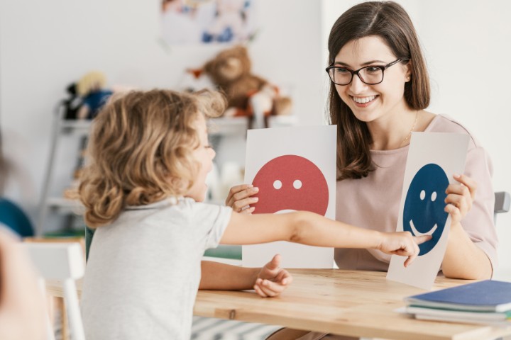 Pediatric therapist using emotion cards with a child during autism therapy session