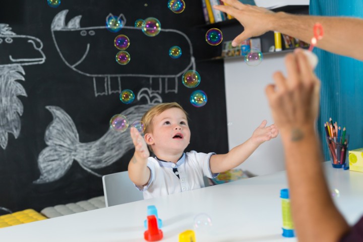 Young boy playing with bubbles during a sensory-based autism therapy session