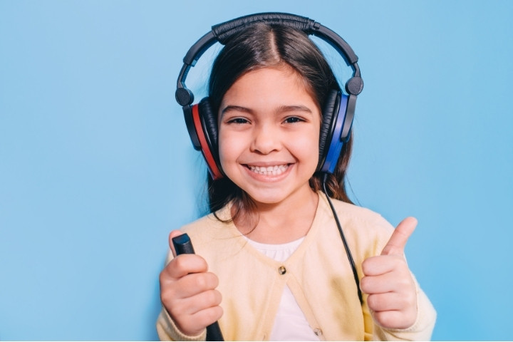A smiling girl wearing headphones during a hearing screening at a Dallas family audiology clinic