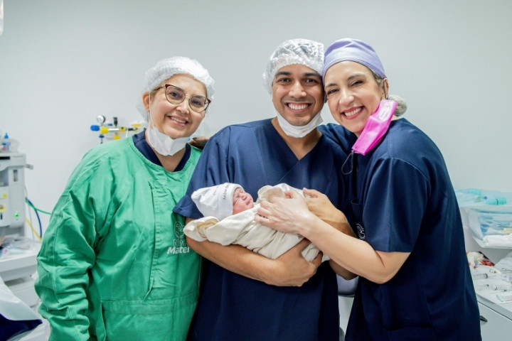 Pediatric care team smiling while holding a newborn after completing a lingual frenectomy procedure