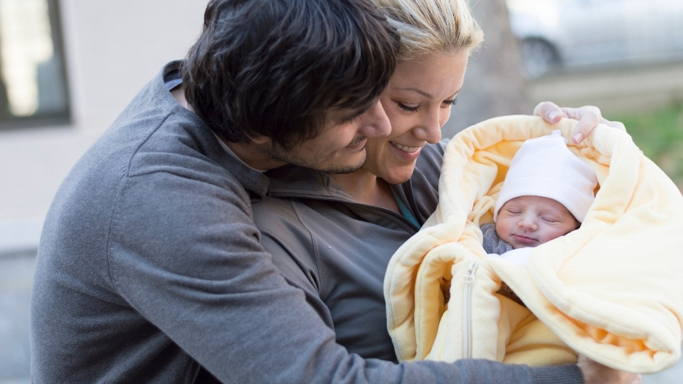 Plano parents holding their newborn while preparing for early hearing care decisions