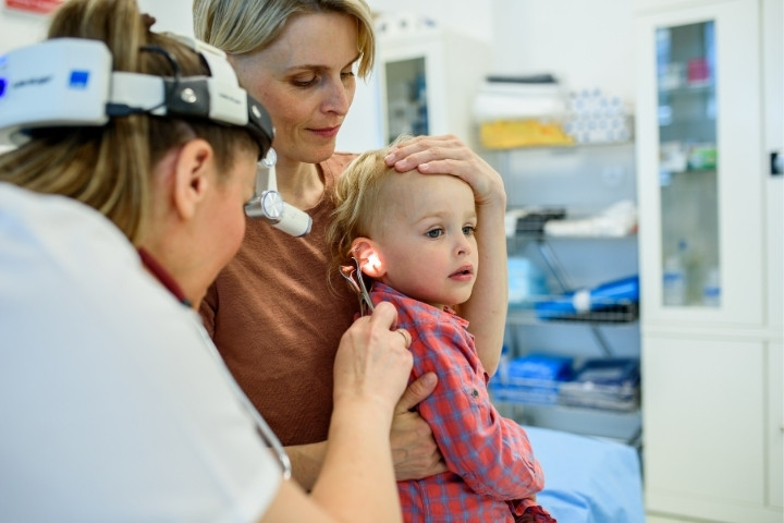 Pediatric specialist examining a toddler’s ear during a hearing checkup