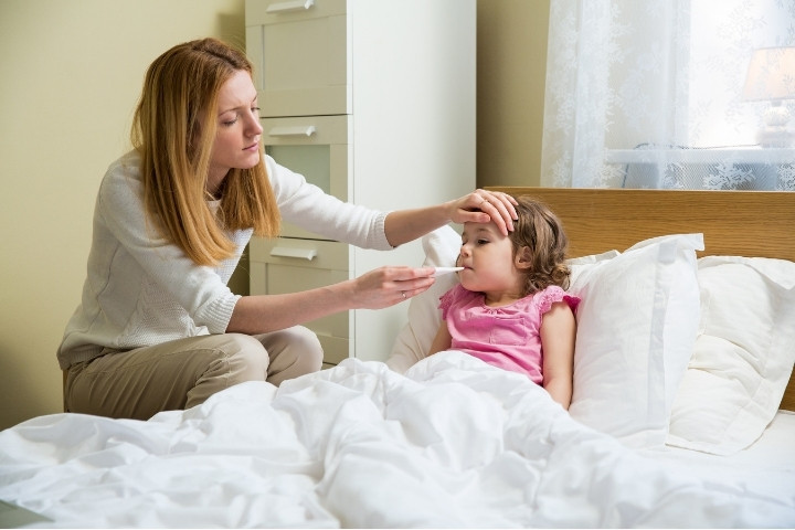 Parent checking a child’s fever while deciding clinic care versus home care