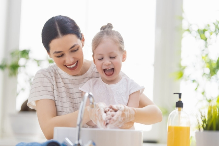 Parent helping a child wash hand with soap, an easy habit to reduce wart spread