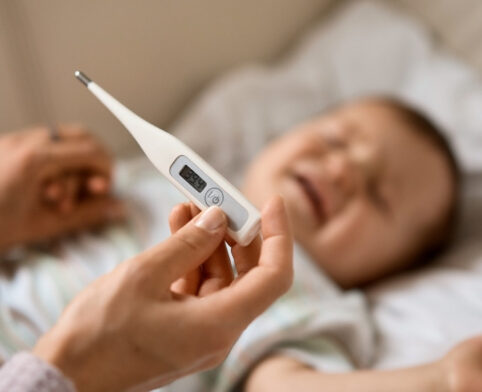 Parent using a digital thermometer to determine a baby’s fever temperature