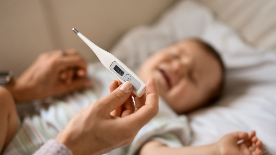 Parent using a digital thermometer to determine a baby’s fever temperature