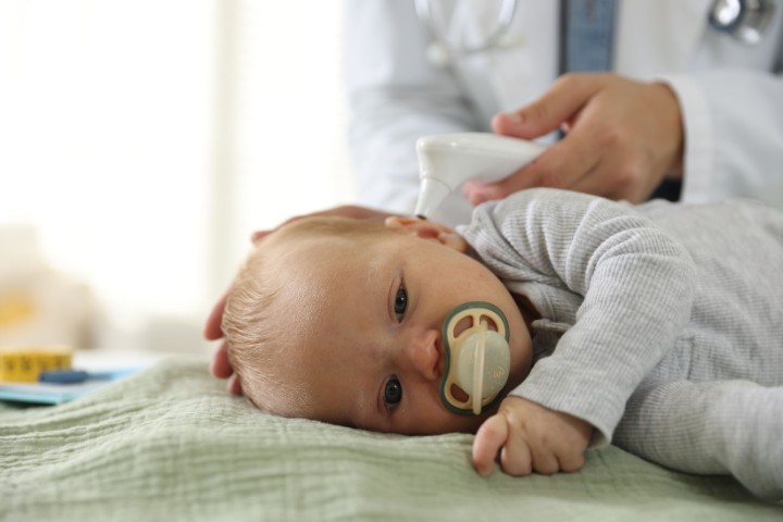 Medical professional checking an infant’s temperature with a forehead thermometer