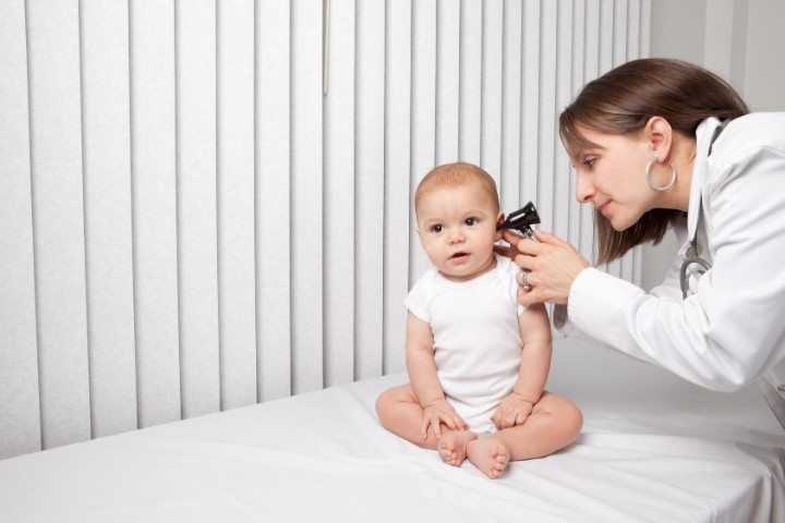 Pediatrician checking ear infection before hearing referral