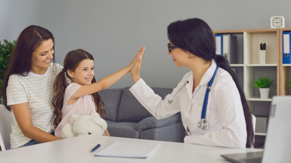 Child and parent meet with a pediatrician during a well child appointment at a children's clinic