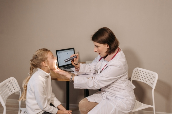 Plano pediatrician performs a throat check during a child wellness exam