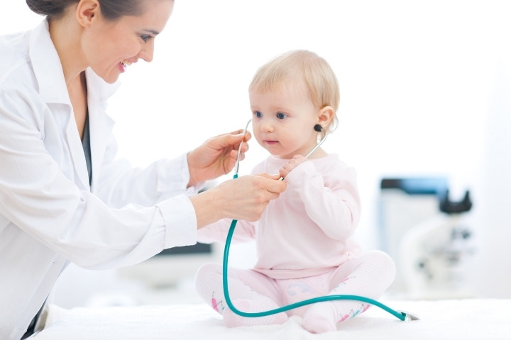 Toddler sits with a pediatrician during a well child visit and developmental check in Dallas