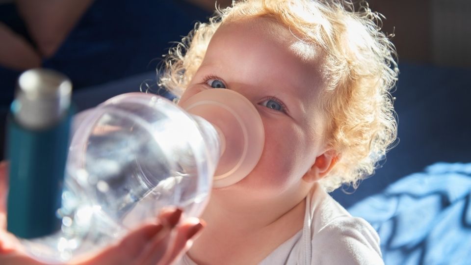 Child receiving asthma medication through an inhaler with a spacer mask