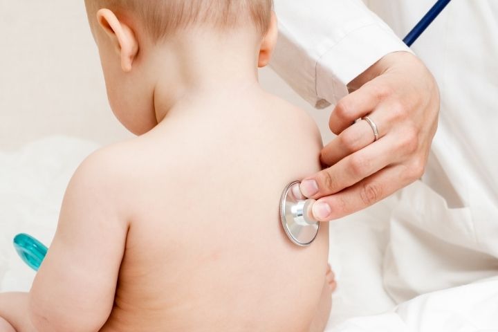 Pediatric healthcare provider listening to a young child's lungs for breathing problems