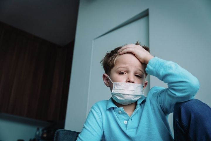 Boy wearing a face mask while experiencing flu symptoms at home