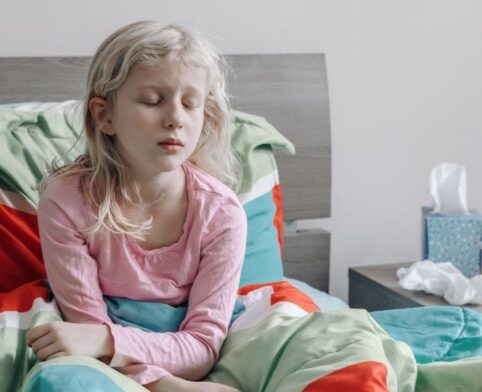 Child resting in bed while feeling unwell with flu symptoms