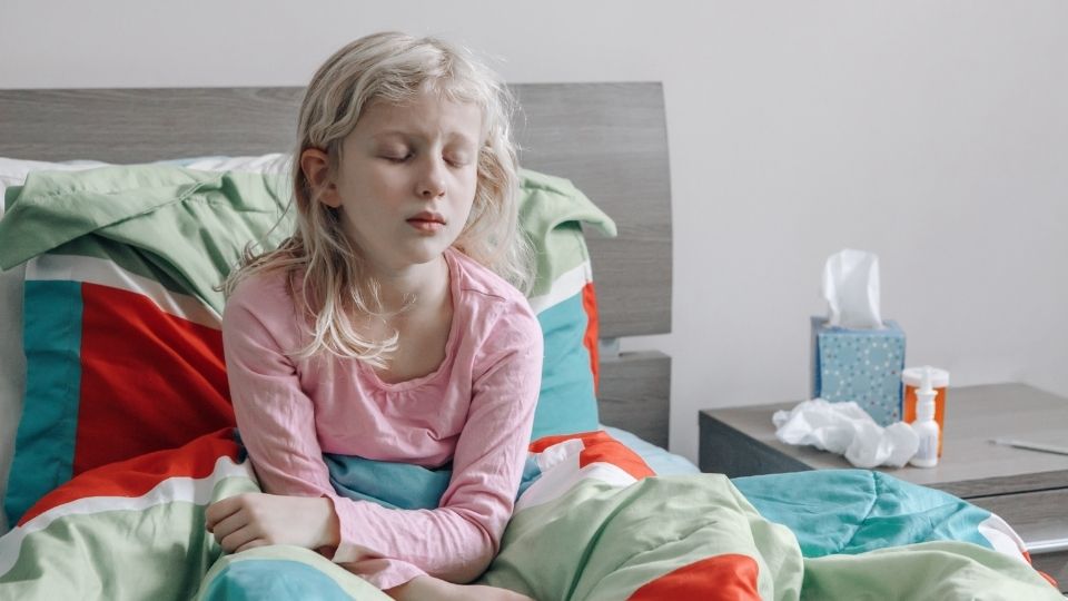 Child resting in bed while feeling unwell with flu symptoms